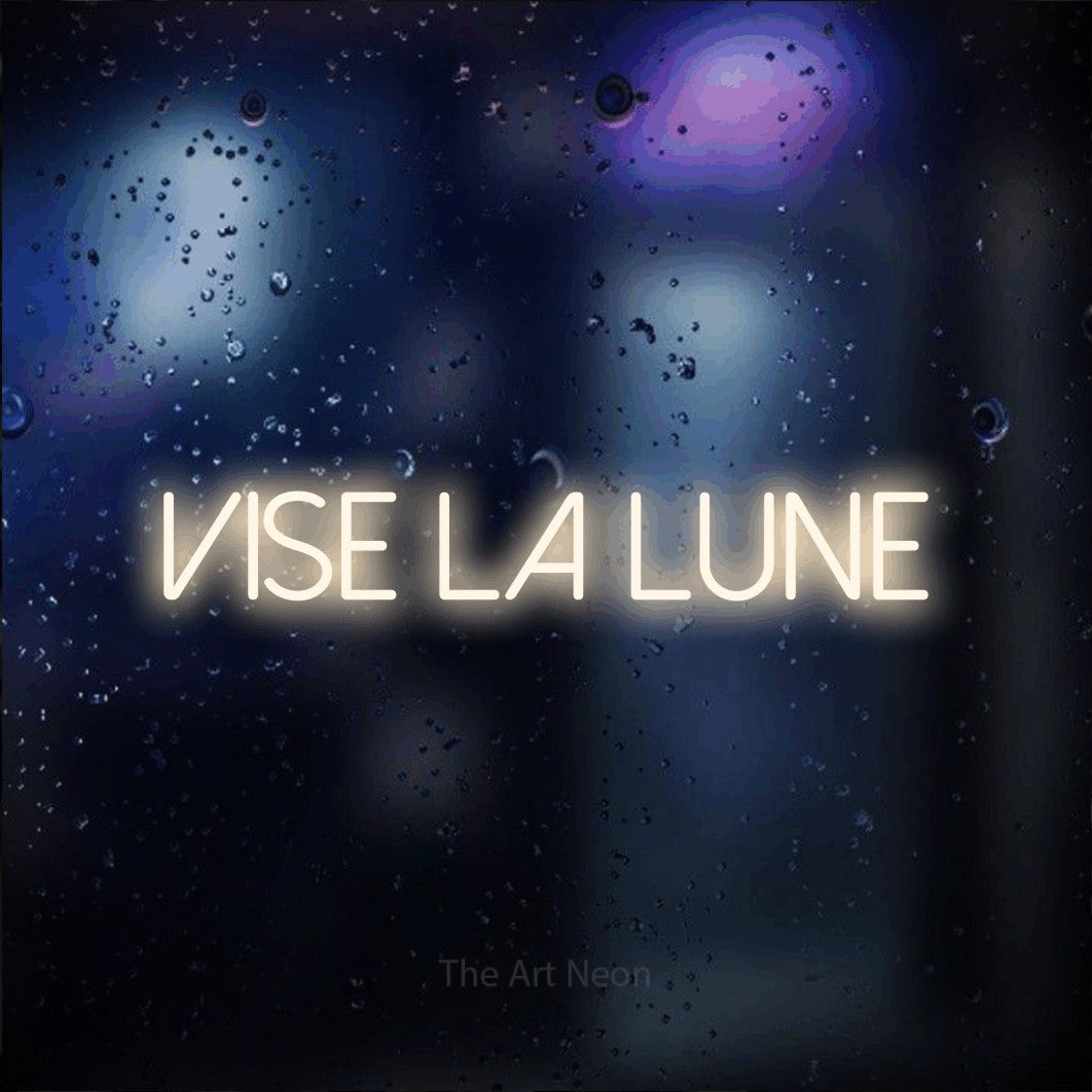 “Vise la lune” LED neon sign in warm white, with thin sans-serif lettering, shown against glass with blue and purple reflections.