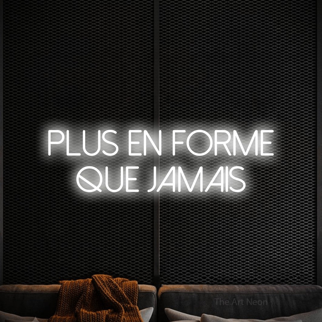 “Plus en forme que jamais” LED neon sign in cool white, with thin sans-serif lettering across 2 lines, shown against a modern dark-toned seating area.