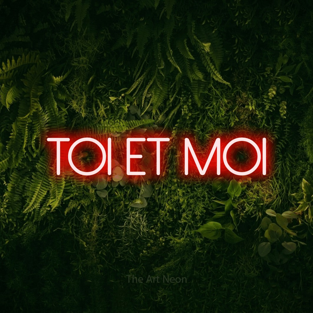 “Toi et moi” LED neon sign in red, with thin sans-serif lettering, shown against a dark moss and forest backdrop.