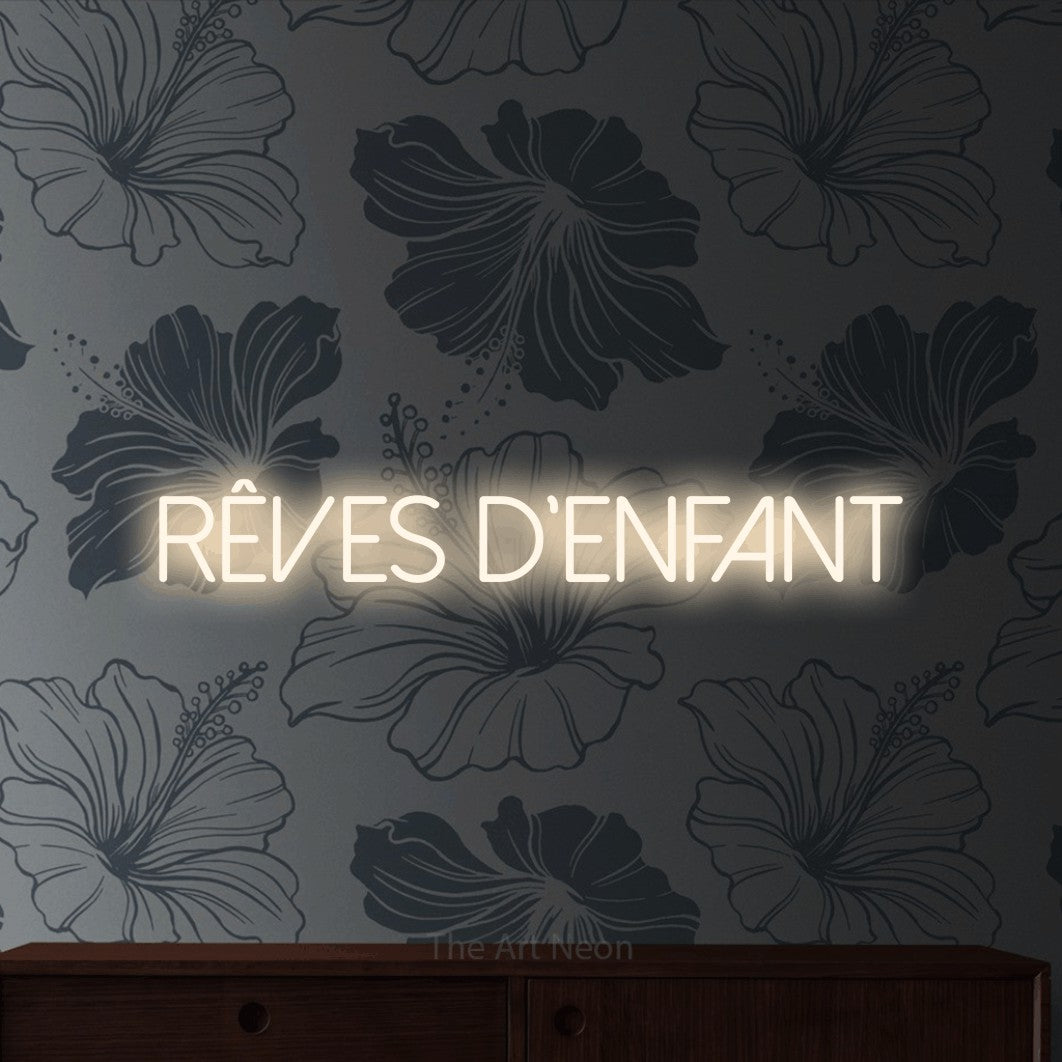 “Rêves d'enfant” LED neon sign in warm white, with thin sans-serif lettering, shown against a grey floral-patterned wall.