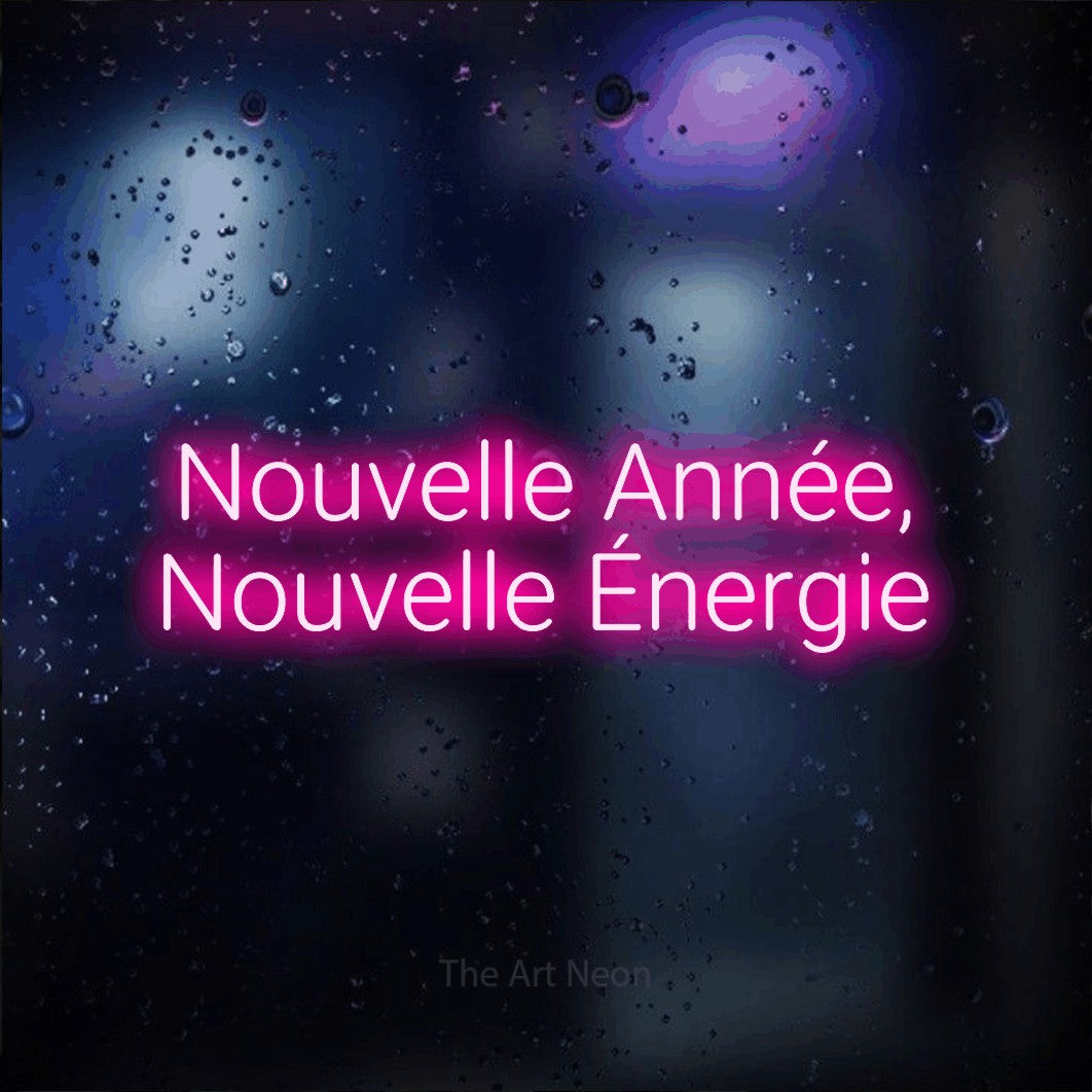 “Nouvelle année, nouvelle énergie” LED neon sign in hot pink, with rounded sans-serif lettering across 2 lines, shown against glass with blue and purple reflections.