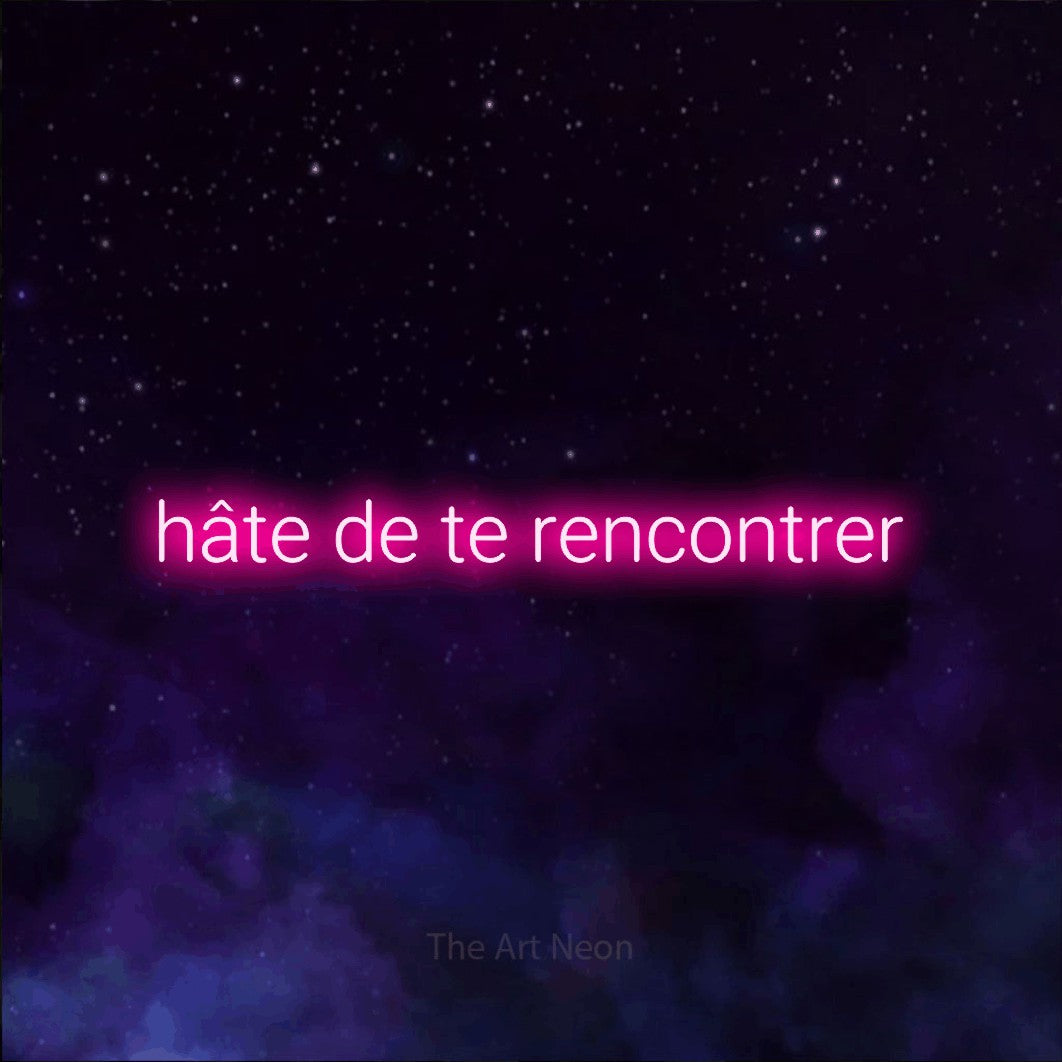 “Hâte de te rencontrer” LED neon sign in hot pink, with rounded sans-serif lettering, shown against a purple galaxy backdrop.