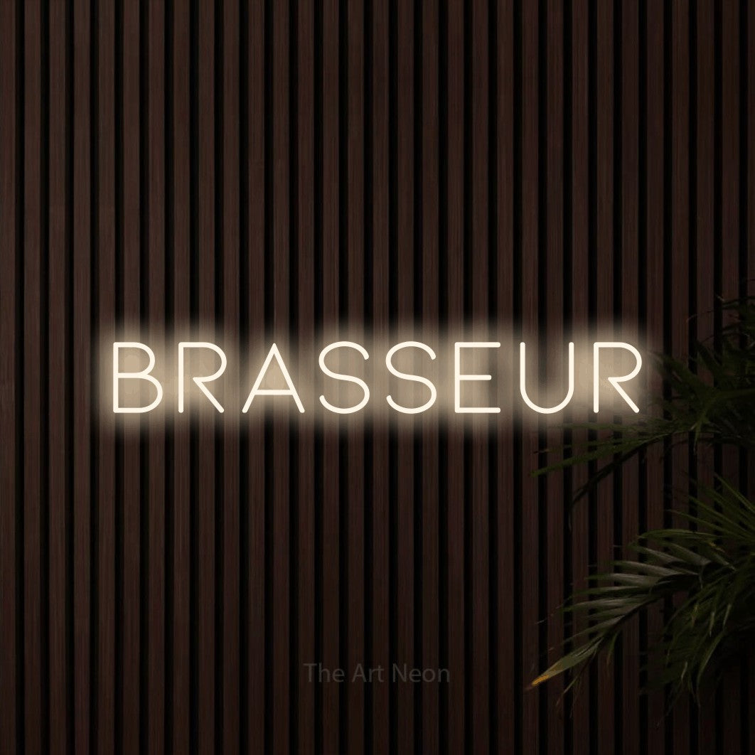 “Brasseur” LED neon sign in warm white, with thin, widely spaced lettering, shown against dark wooden wall slats.
