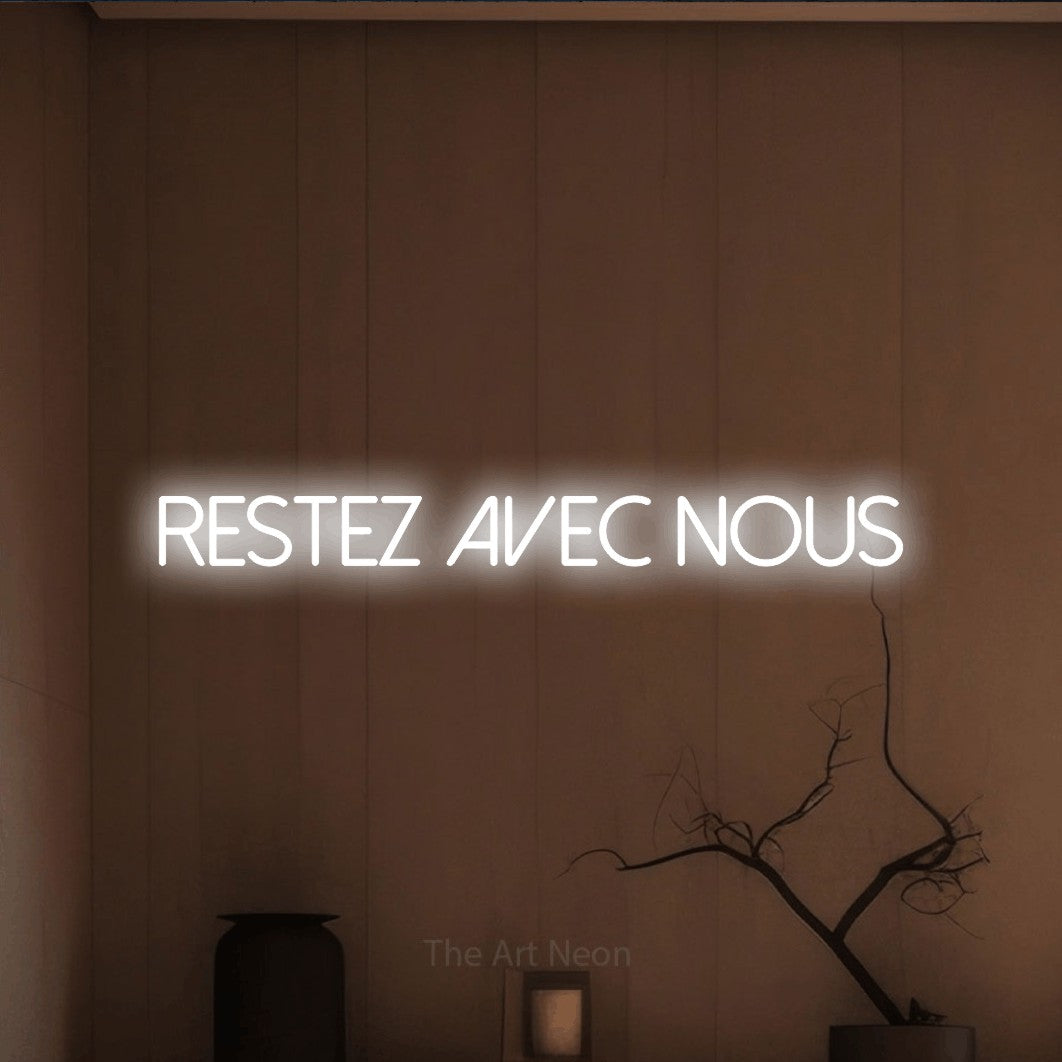 Décoration murale en néon LED « Restez avec nous » en blanc froid, en lettres fines sans empattement, installée dans un intérieur épuré aux tons terre, pour un hôtel.
