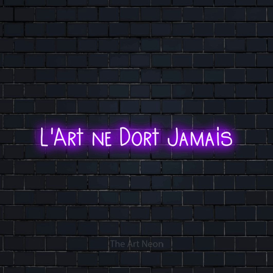 Composition en néon LED « L'art ne dort jamais » en violet, en lettres étroites dessinées à la main, mise en valeur sur un mur de briques bleu marine foncé, pour un studio de tatouage.