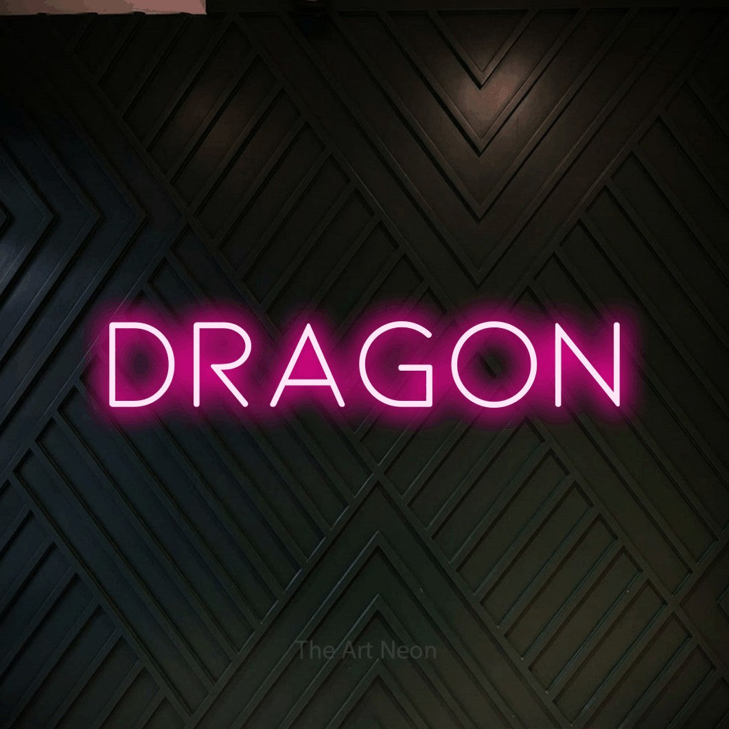 “Dragon” LED neon sign in hot pink, with thin, widely spaced lettering, shown against a black chevron-patterned wood wall.