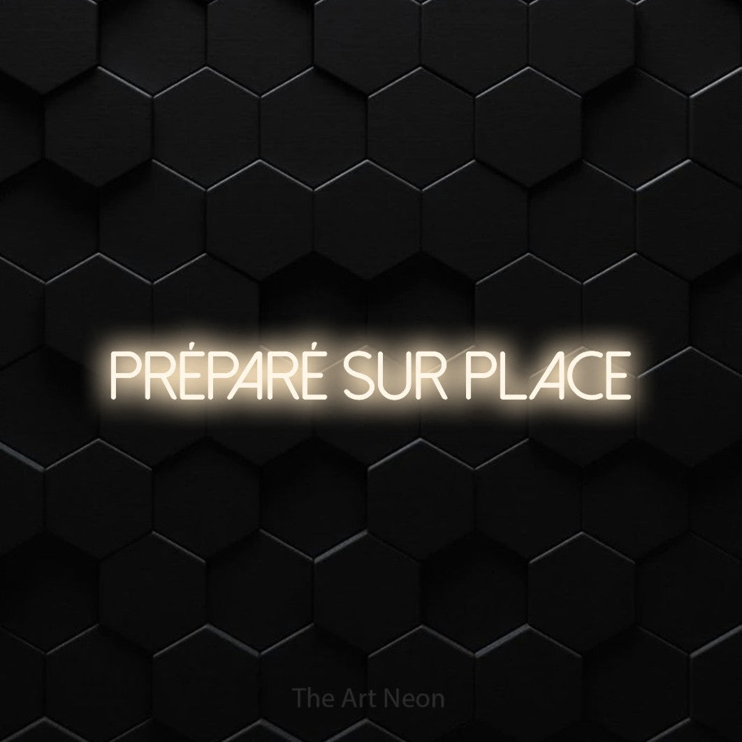 “Préparé sur place” LED neon sign in warm white, with thin sans-serif lettering, shown against black hexagonal wall tiles.