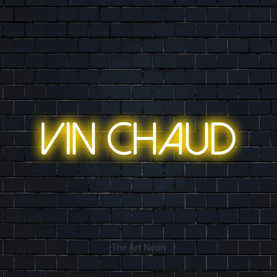 “Vin chaud” LED neon sign in yellow, with thin sans-serif lettering, shown against a dark navy brick wall.