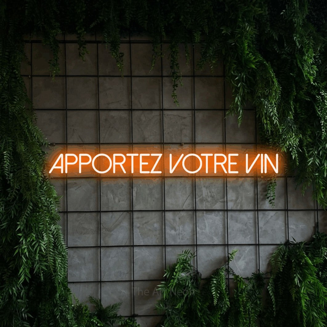 “Apportez votre vin” LED neon sign in orange, with thin sans-serif lettering, shown against an ivy-covered concrete grid.