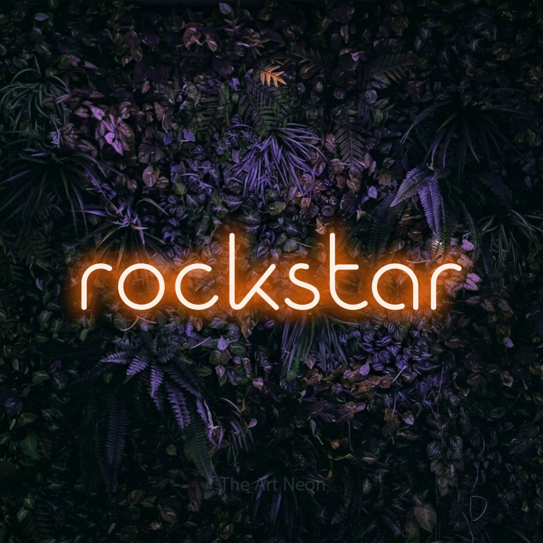 Enseigne néon LED « Rockstar » en orange, en lettres géométriques stylisées, présentée sur un mur sombre aux fleurs violettes, pour une fête.