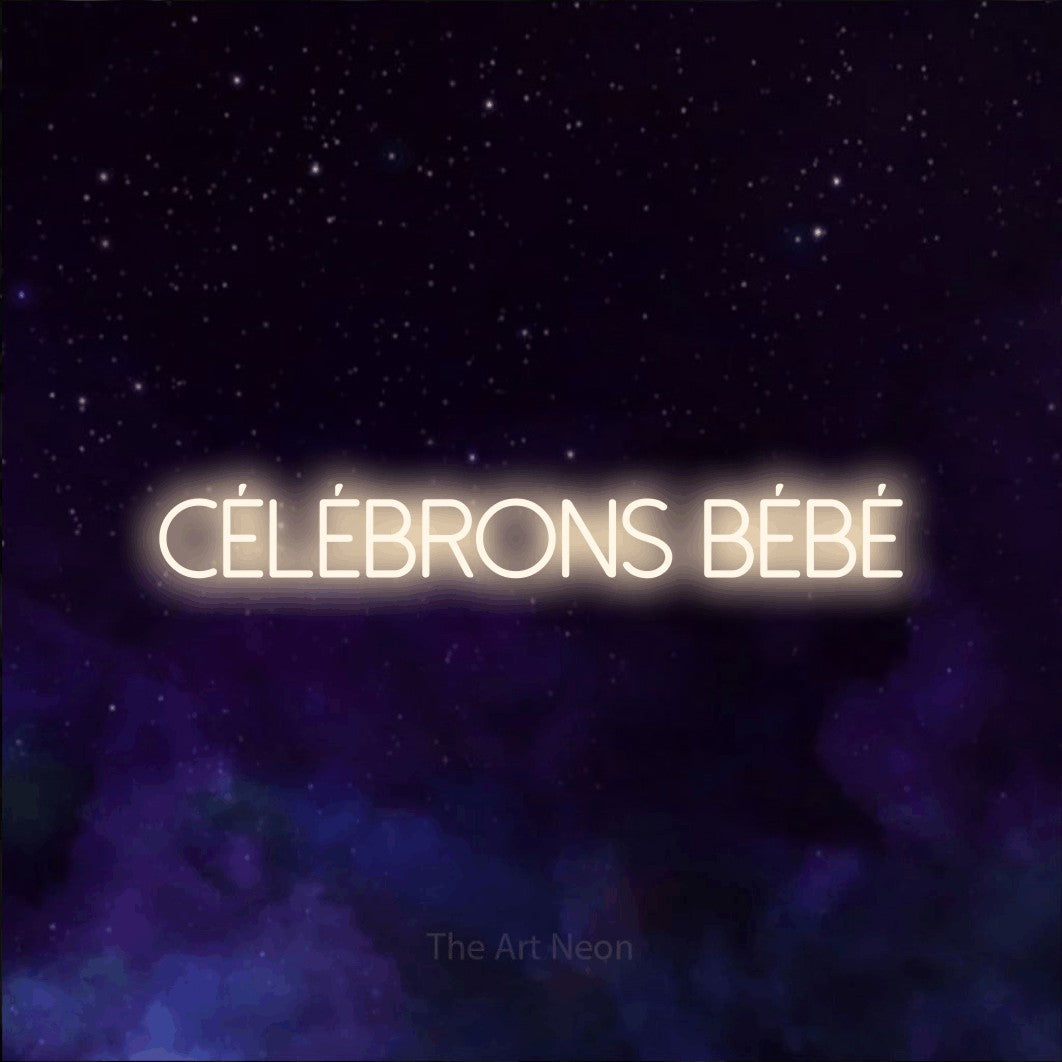 “Célébrons bébé” LED neon sign in warm white, with thin sans-serif lettering, shown against a purple galaxy backdrop.