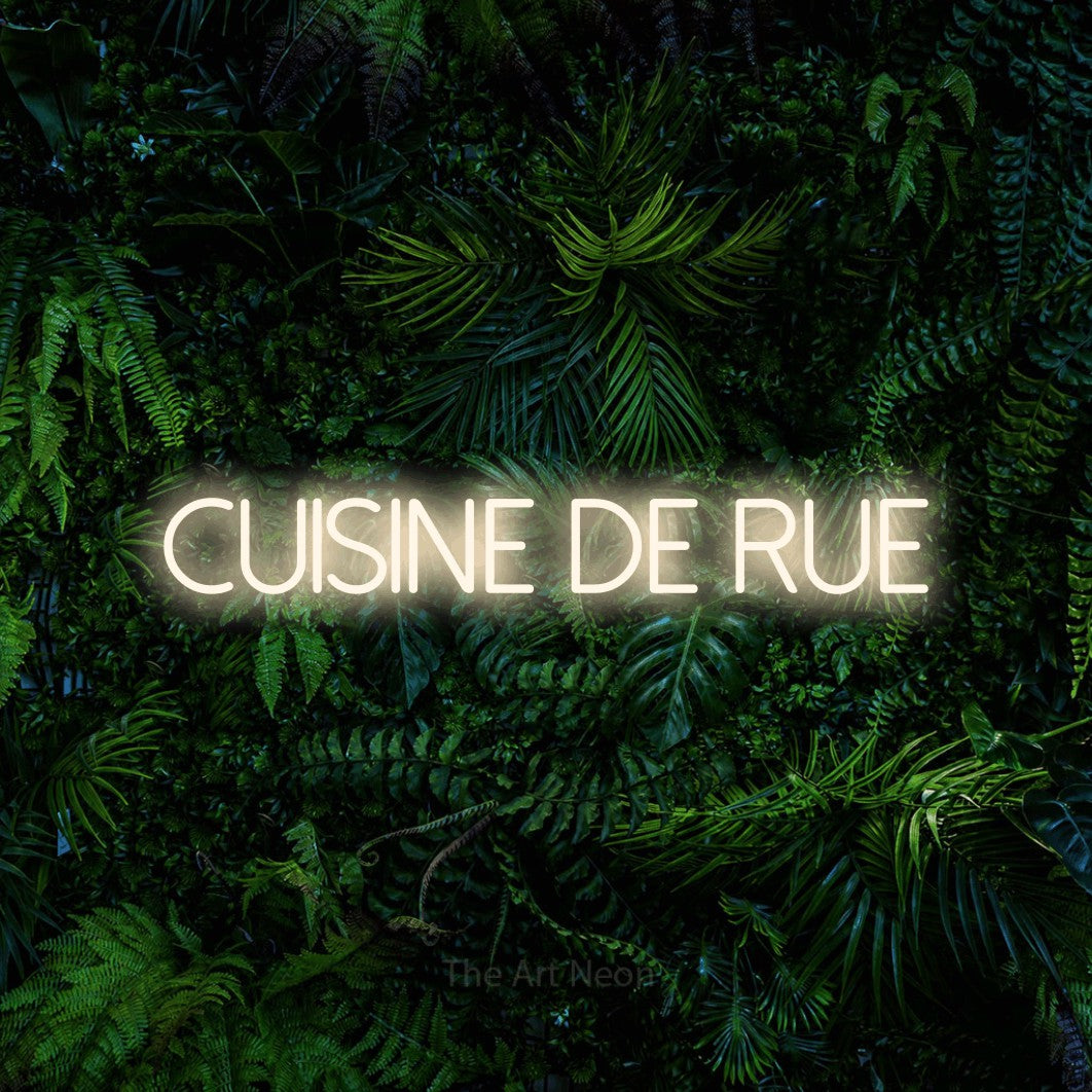 “Cuisine de rue” LED neon sign in warm white, with thin sans-serif lettering, shown against dense tropical foliage.