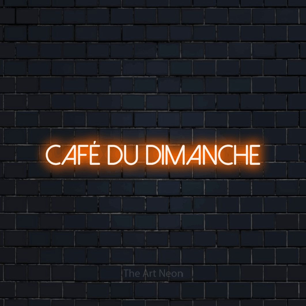 “Café du dimanche” LED neon sign in orange, with thin sans-serif lettering, shown against a dark navy brick wall.