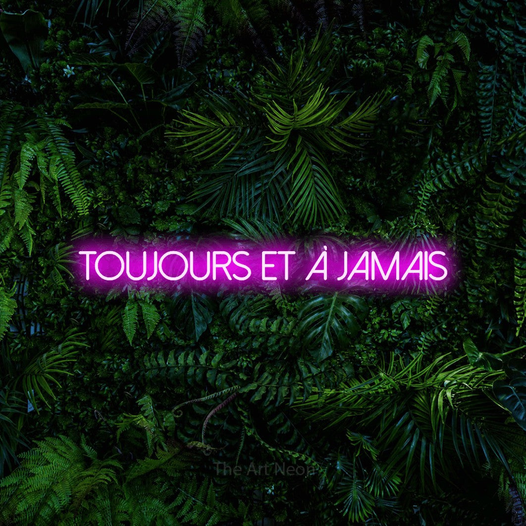 “Toujours et à jamais” LED neon sign in pink, with thin sans-serif lettering, shown against dense tropical foliage.