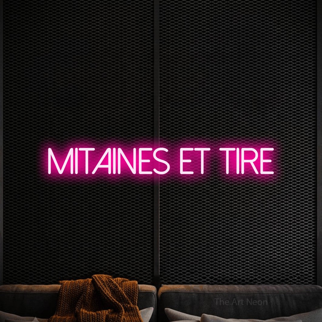 “Mitaines et tire” LED neon sign in hot pink, with thin sans-serif lettering, shown against a modern dark-toned seating area.
