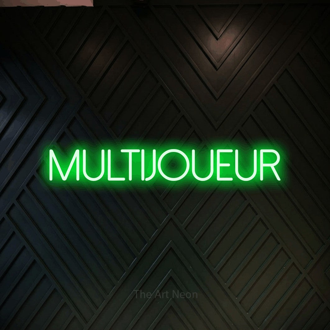 “Multijoueur” LED neon sign in green, with thin sans-serif lettering, shown against a black chevron-patterned wood wall.