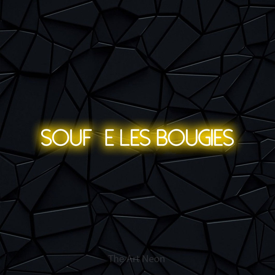 “Souffle les bougies” LED neon sign in yellow, with thin sans-serif lettering, shown against a black polygonal surface.