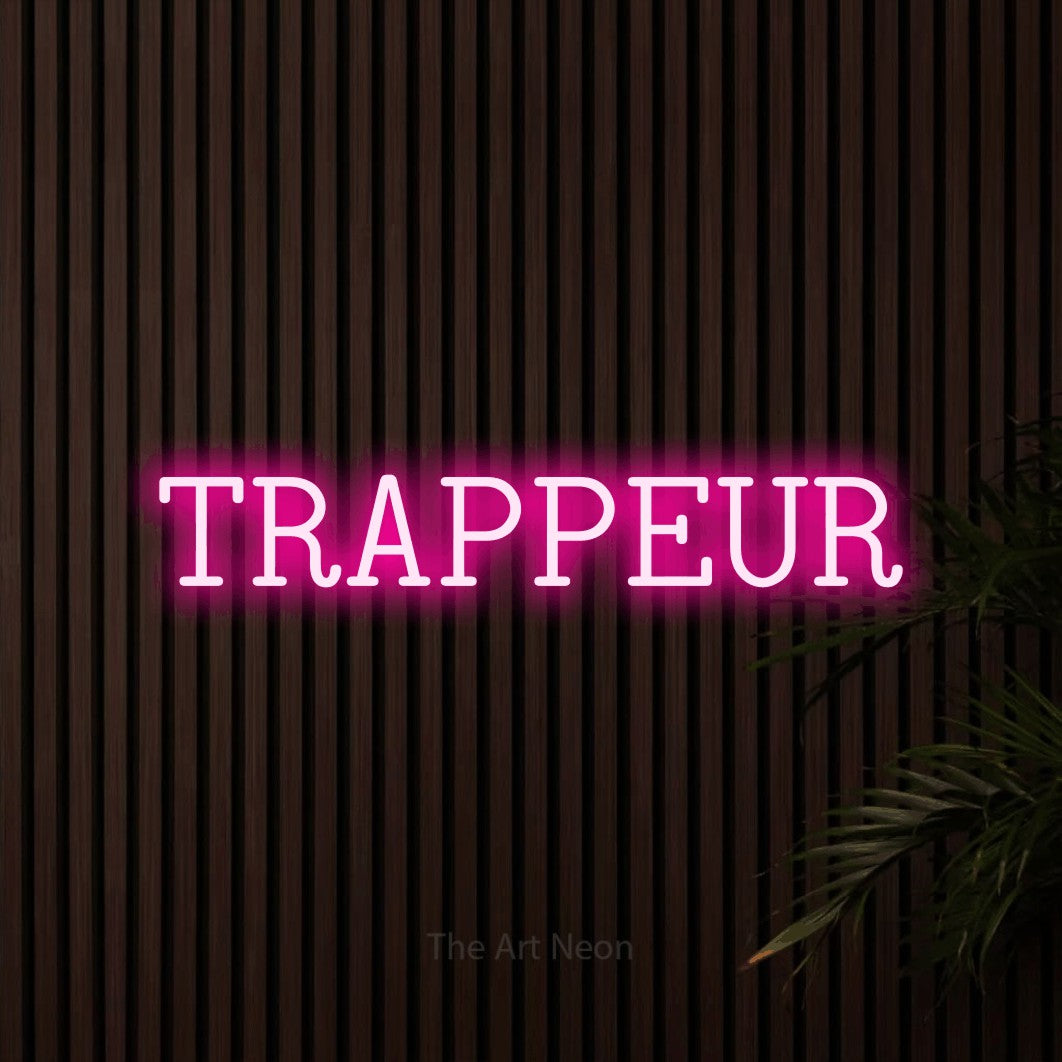 “Trappeur” LED neon sign in hot pink, with typewriter-style lettering, shown against dark wooden wall slats.
