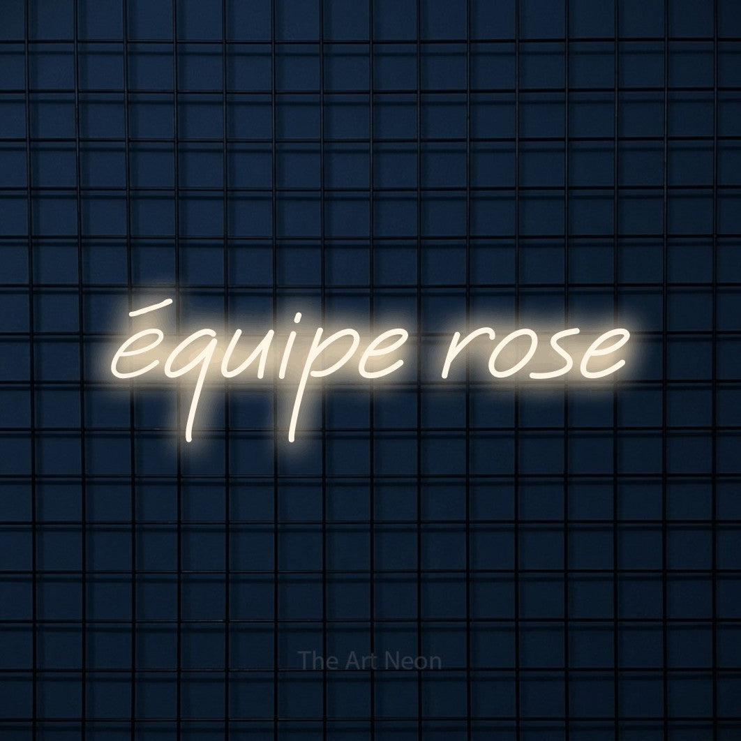 “Équipe rose” LED neon sign in warm white, with slanted cursive lettering, shown against a dark blue grid.