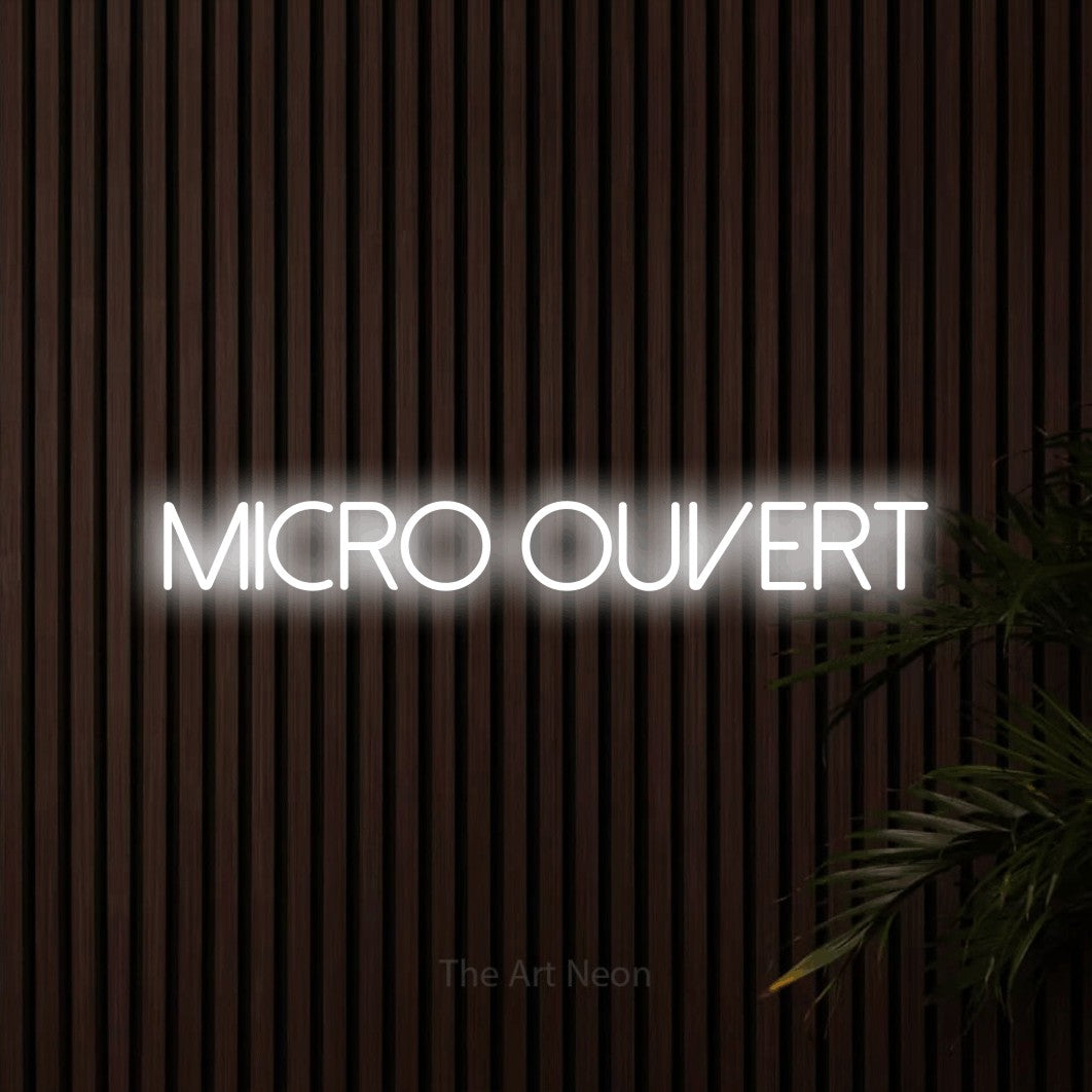 “Micro ouvert” LED neon sign in cool white, with thin sans-serif lettering, shown against dark wooden wall slats.
