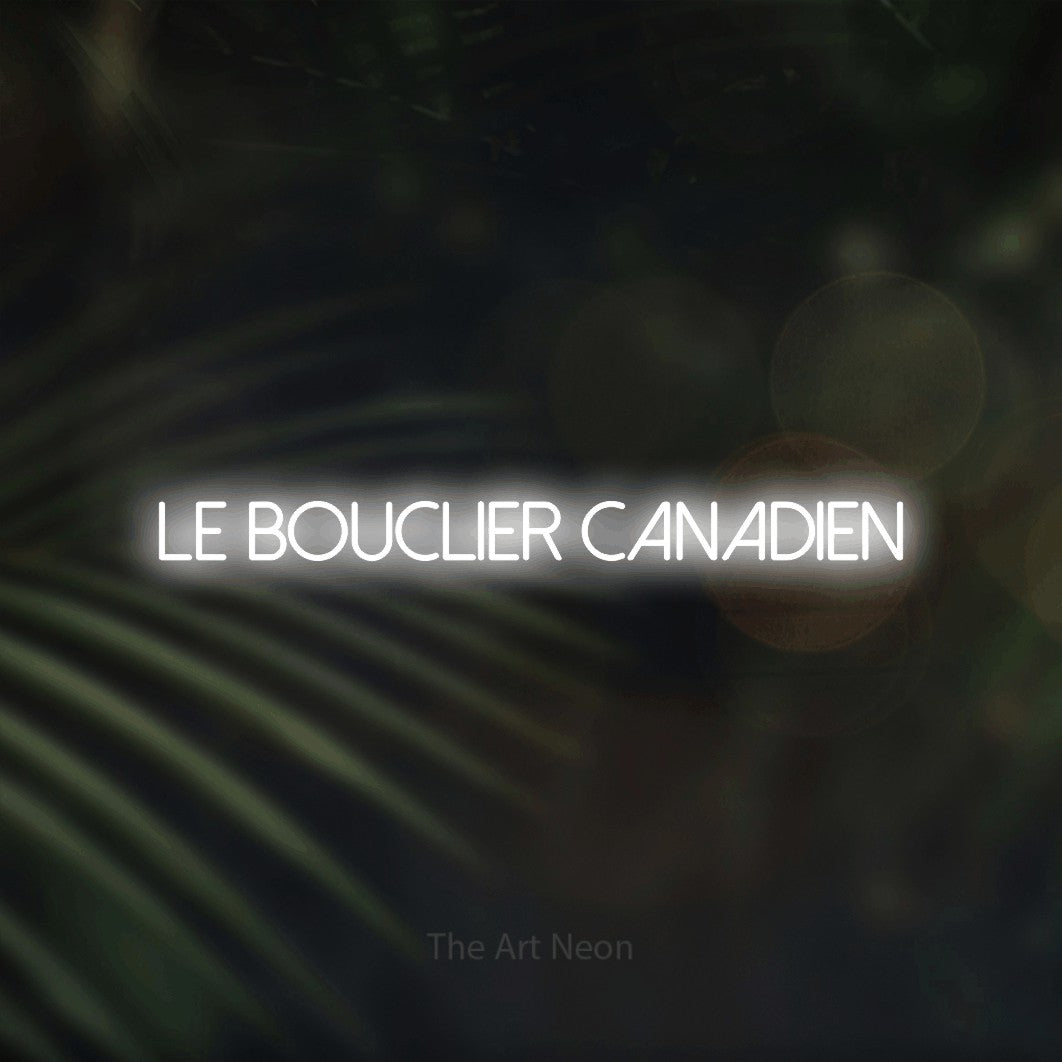 “Le bouclier canadien” LED neon sign in cool white, with thin sans-serif lettering, shown against a blurred palm and bokeh-light backdrop.