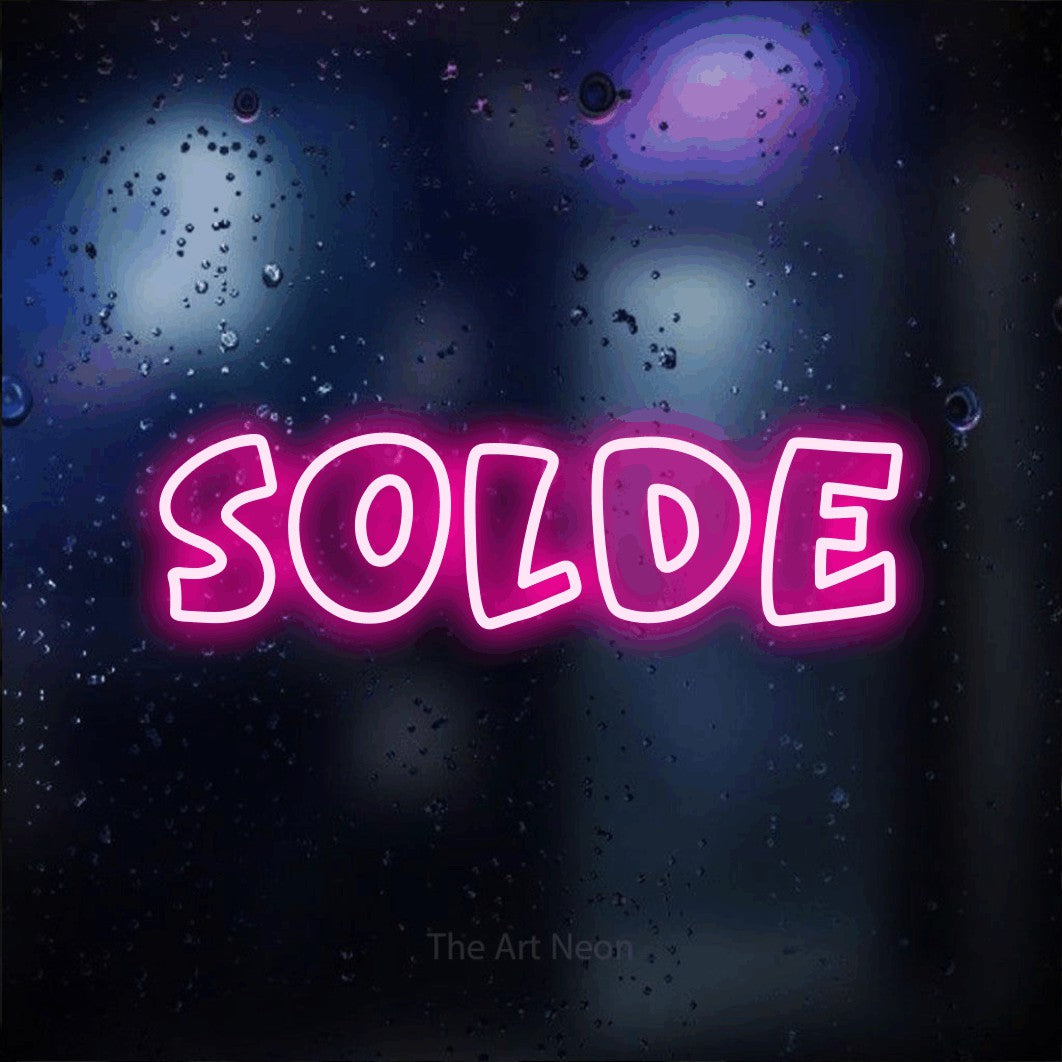 “Solde” LED neon sign in hot pink, with rounded outline lettering, shown against glass with blue and purple reflections.