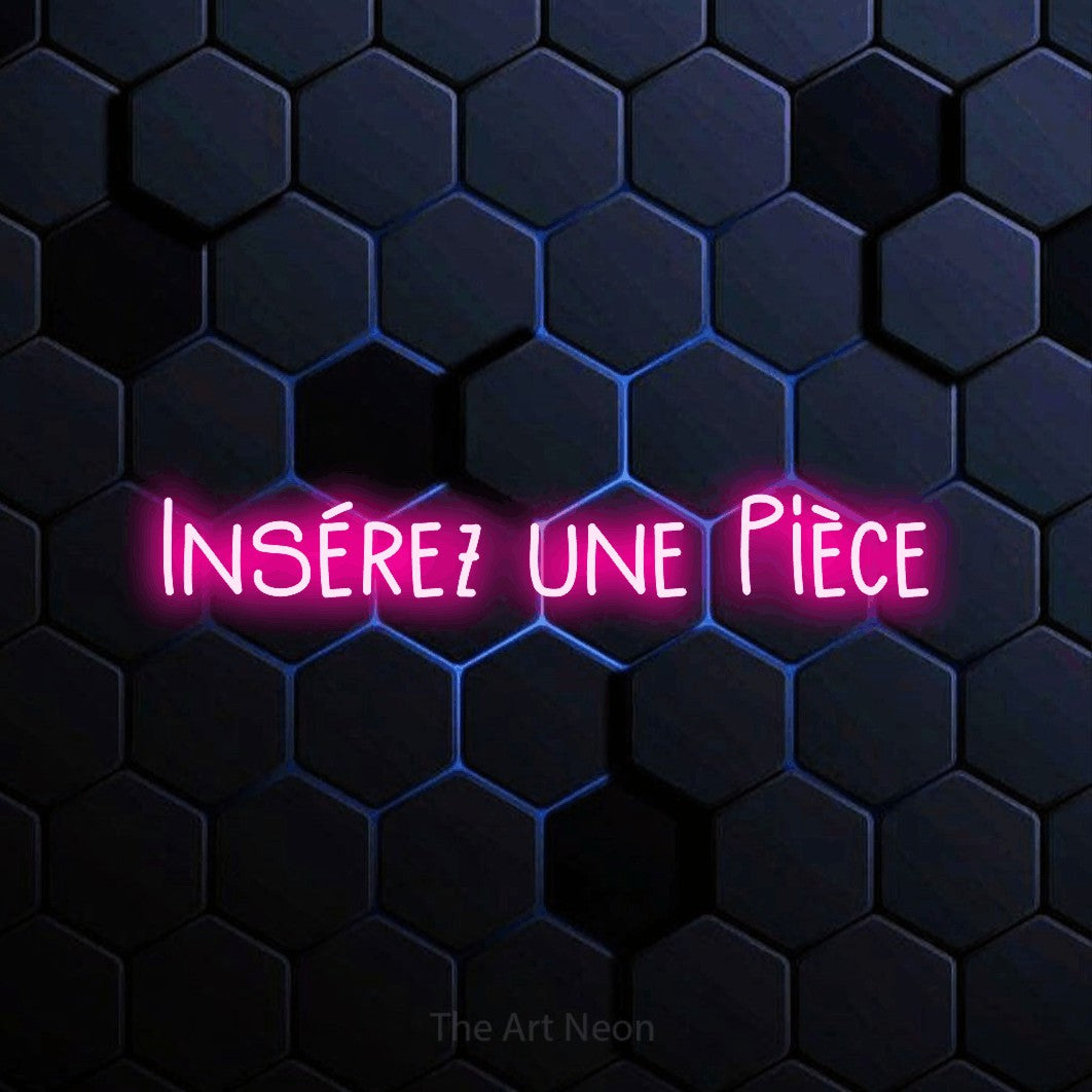 “Insérez une pièce” LED neon sign in hot pink, with narrow hand-drawn lettering, shown against a dark blue honeycomb pattern.