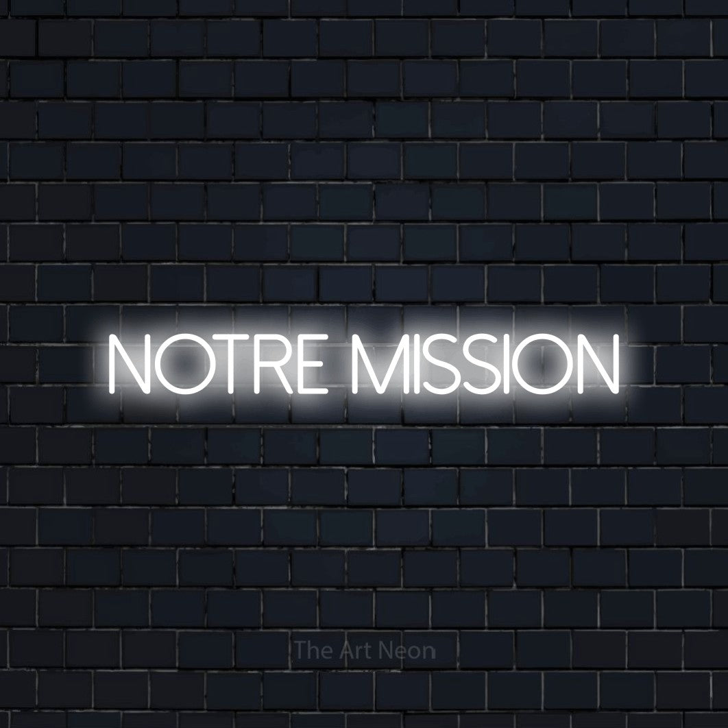 “Notre mission” LED neon sign in cool white, with thin sans-serif lettering, shown against a dark navy brick wall.