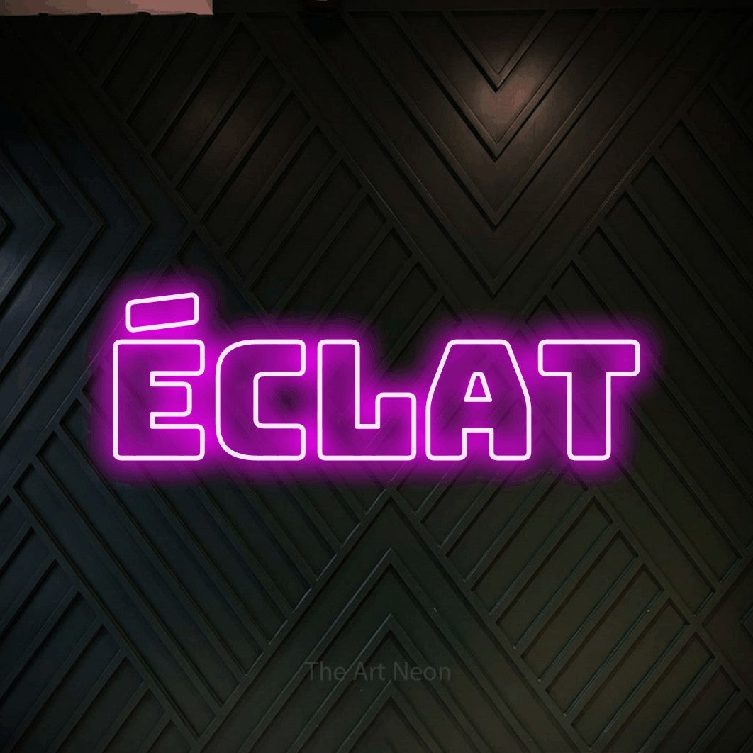 Lettrage en néon LED « Éclat » en rose, en typographie contour épaisse, présenté sur un mur en bois noir à motif chevron, pour un salon de beauté.