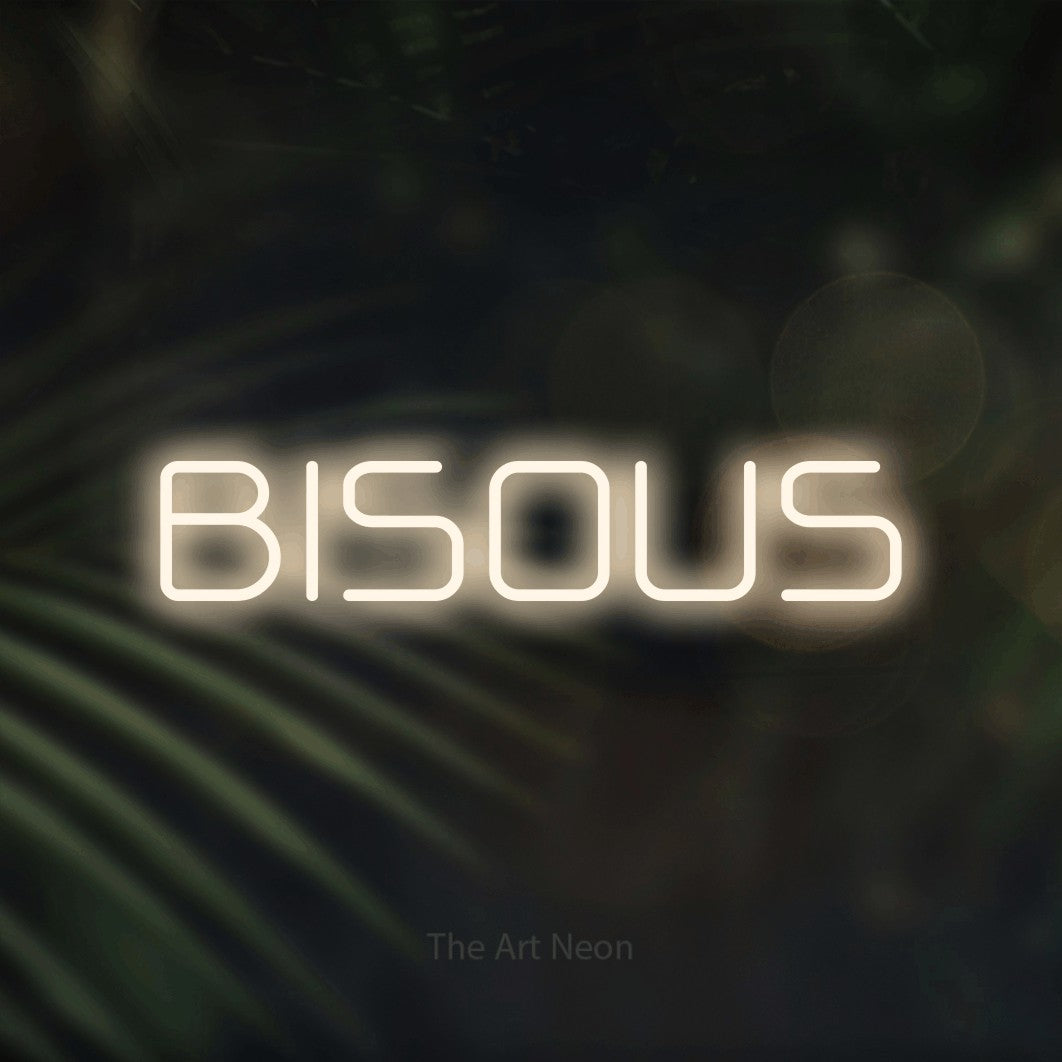 “Bisous” LED neon sign in warm white, with rounded geometric lettering, shown against a blurred palm and bokeh-light backdrop.
