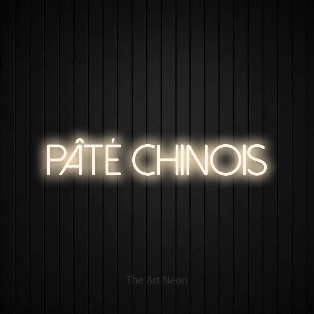 Composition en néon LED « Pâté chinois » en blanc chaud, en lettres fines sans empattement, mise en valeur sur un mur de lattes verticales noires, pour un décor canadien.
