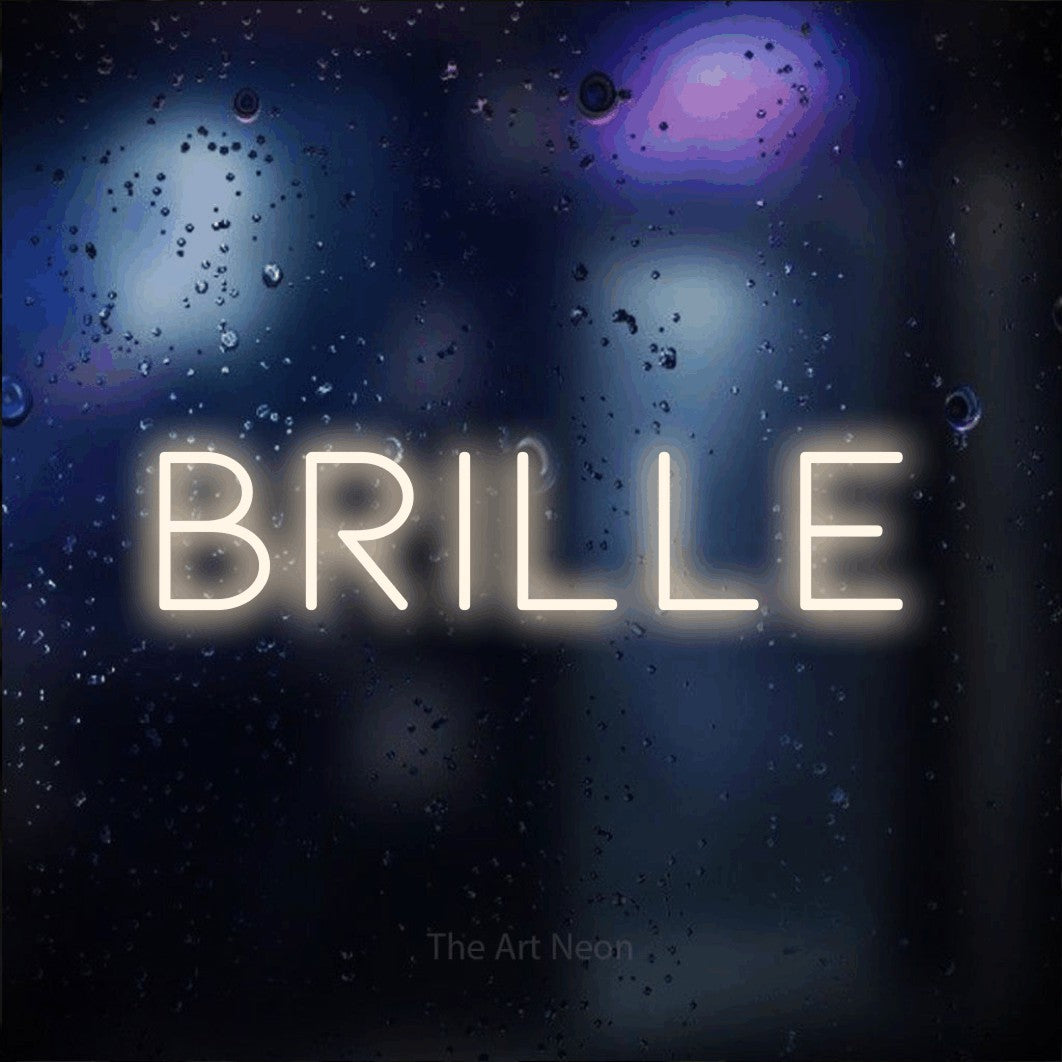 “Brille” LED neon sign in warm white, with thin, widely spaced lettering, shown against glass with blue and purple reflections.