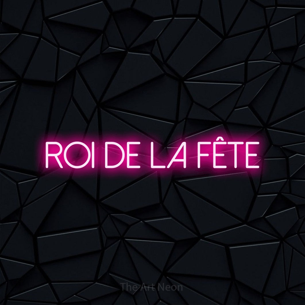 “Roi de la fête” LED neon sign in hot pink, with thin sans-serif lettering, shown against a black polygonal surface.