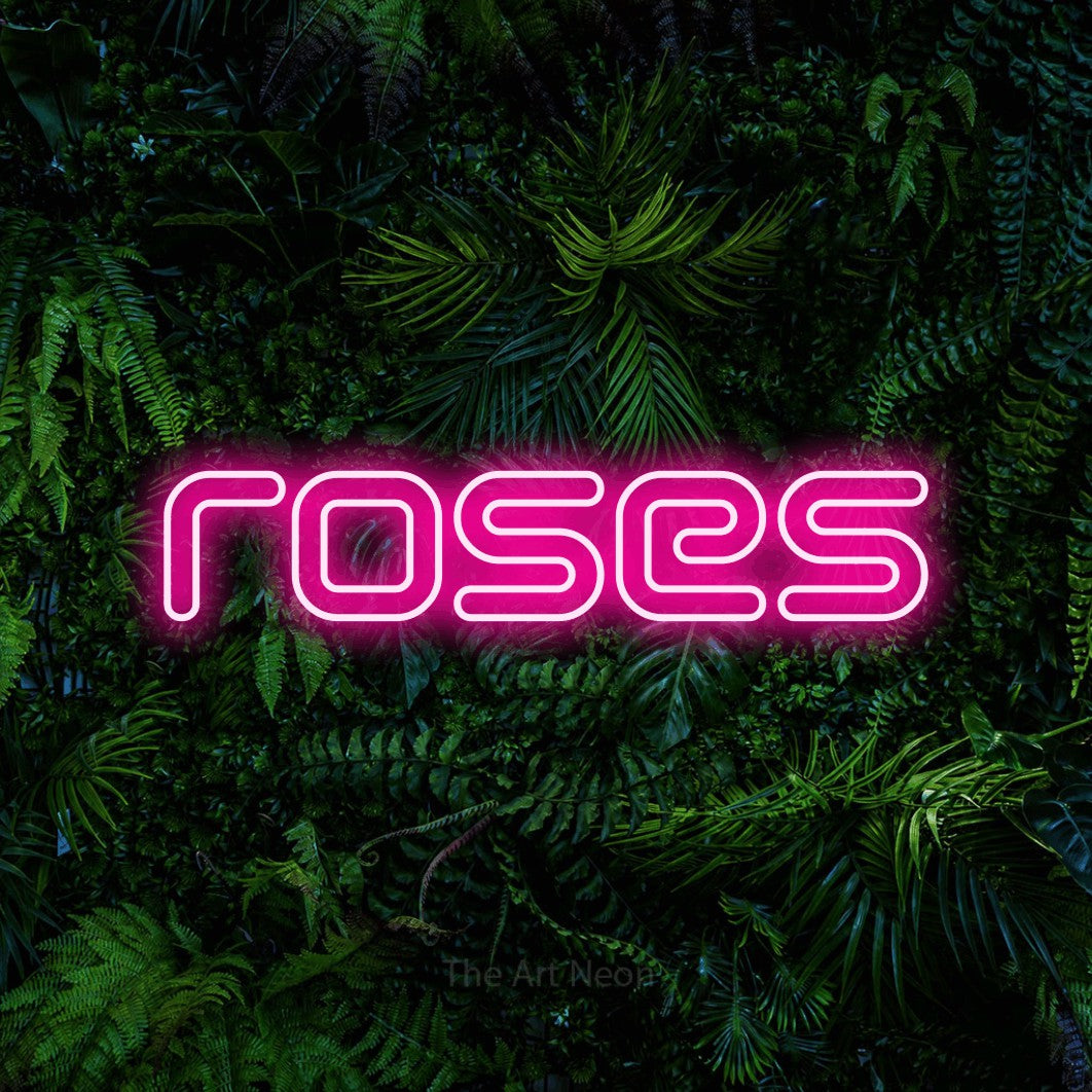 “Roses” LED neon sign in hot pink, with futuristic double-line lettering, shown against dense tropical foliage.