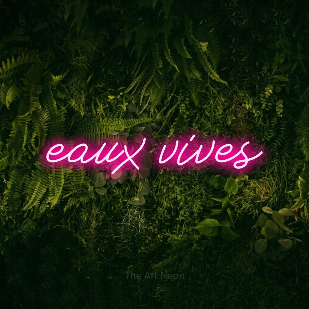 “Eaux vives” LED neon sign in hot pink, with cursive lettering, shown against a dark moss and forest backdrop.