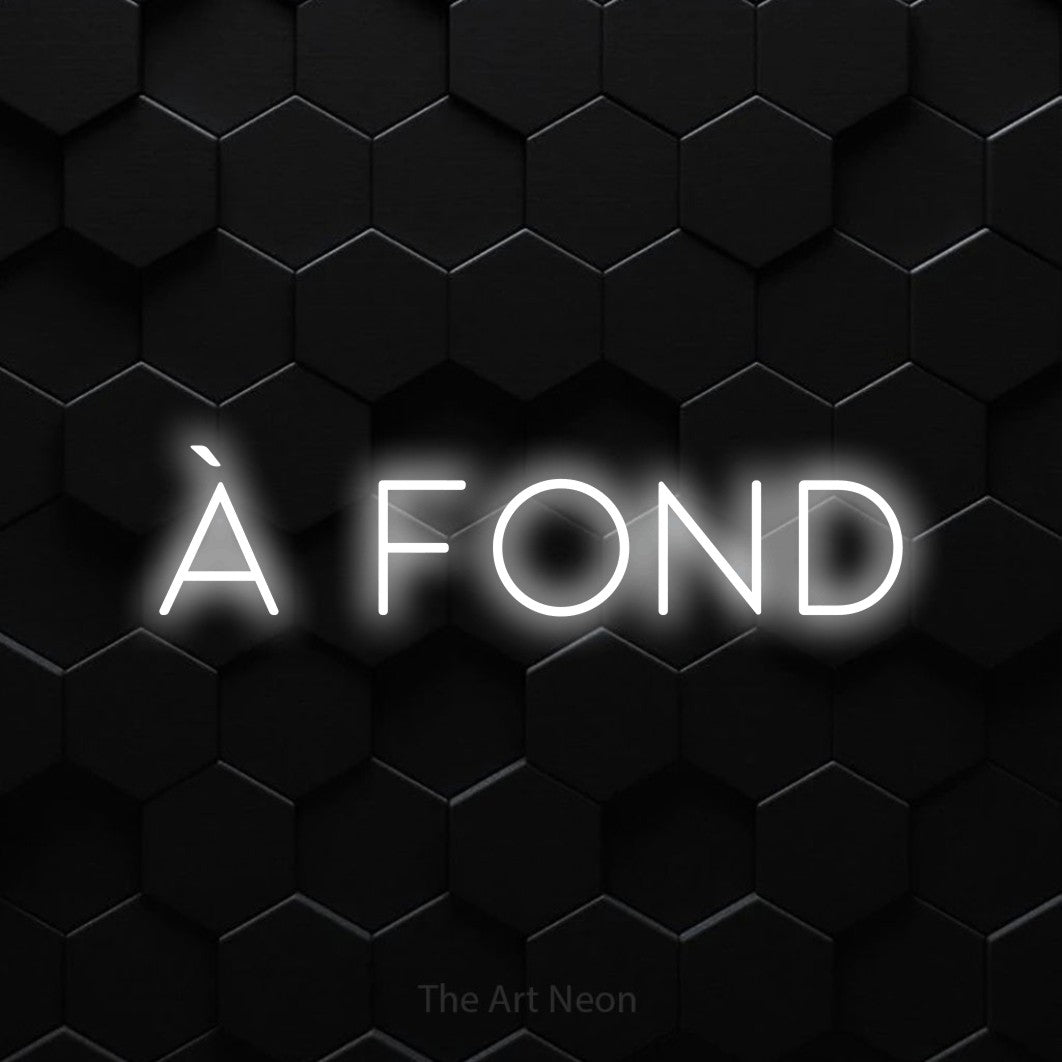 “À fond” LED neon sign in cool white, with thin, widely spaced lettering, shown against black hexagonal wall tiles.