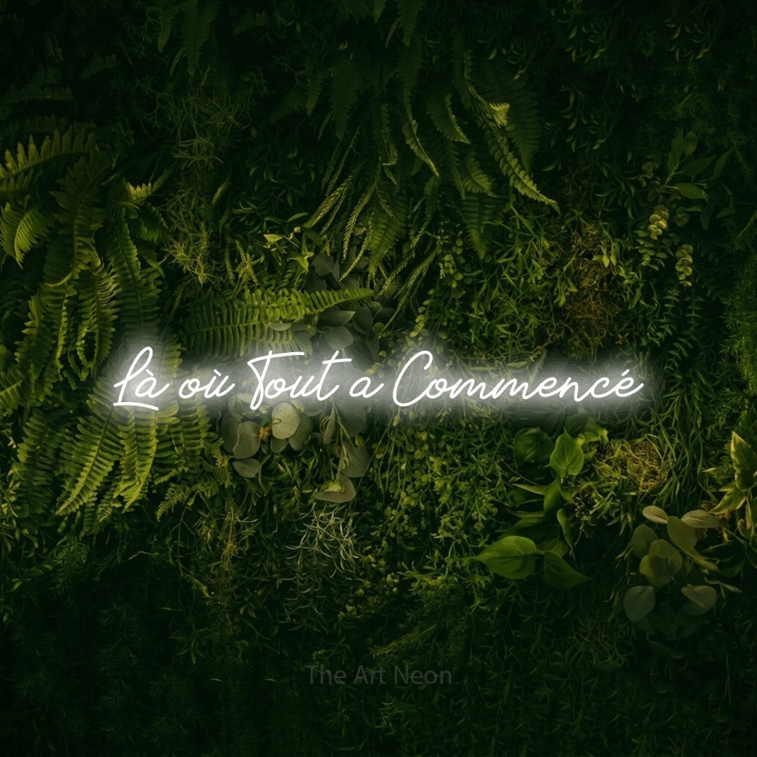 “Là où tout a commencé” LED neon sign in cool white, with cursive lettering, shown against a dark moss and forest backdrop.