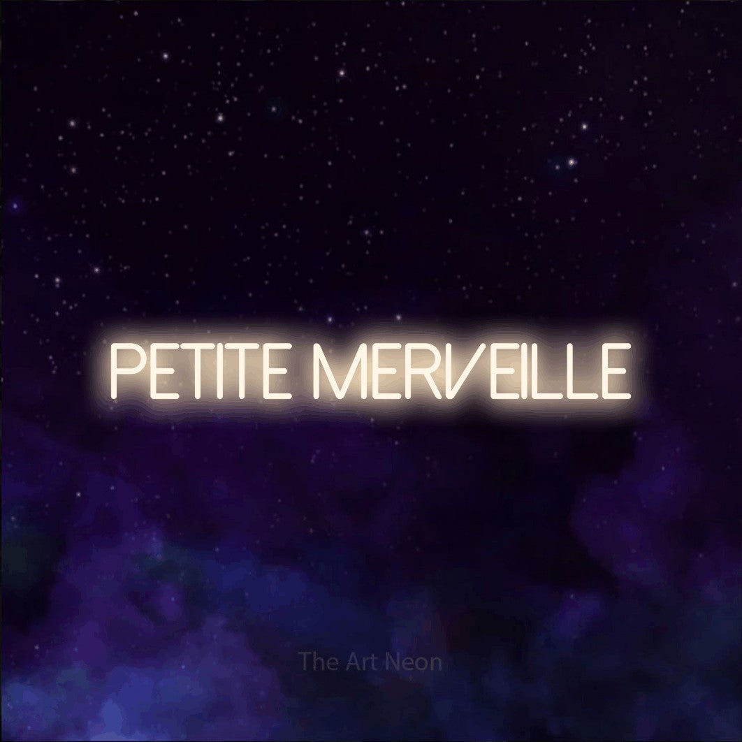“Petite merveille” LED neon sign in warm white, with thin sans-serif lettering, shown against a purple galaxy backdrop.