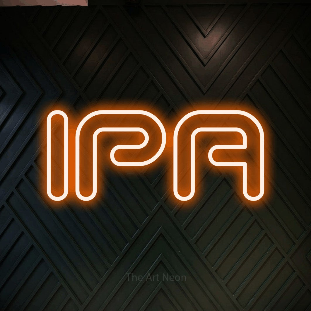 Néon LED « IPA » en orange, en lettres futuristes à double trait, mis en scène sur un mur en bois noir à motif chevron, pour une microbrasserie.