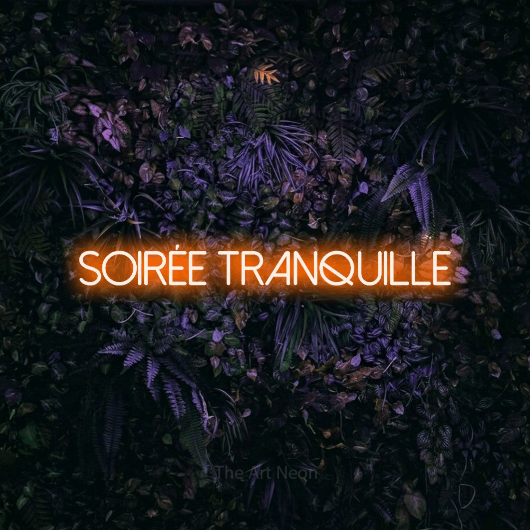 Enseigne néon LED « Soirée tranquille » en orange, en lettres fines sans empattement, présentée sur un mur sombre aux fleurs violettes, pour un salon.