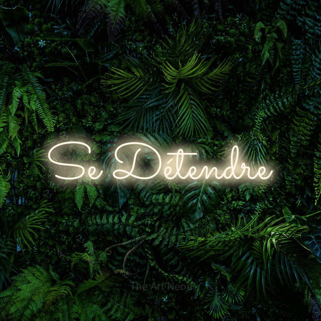“Se détendre” LED neon sign in warm white, with looped cursive lettering, shown against dense tropical foliage.