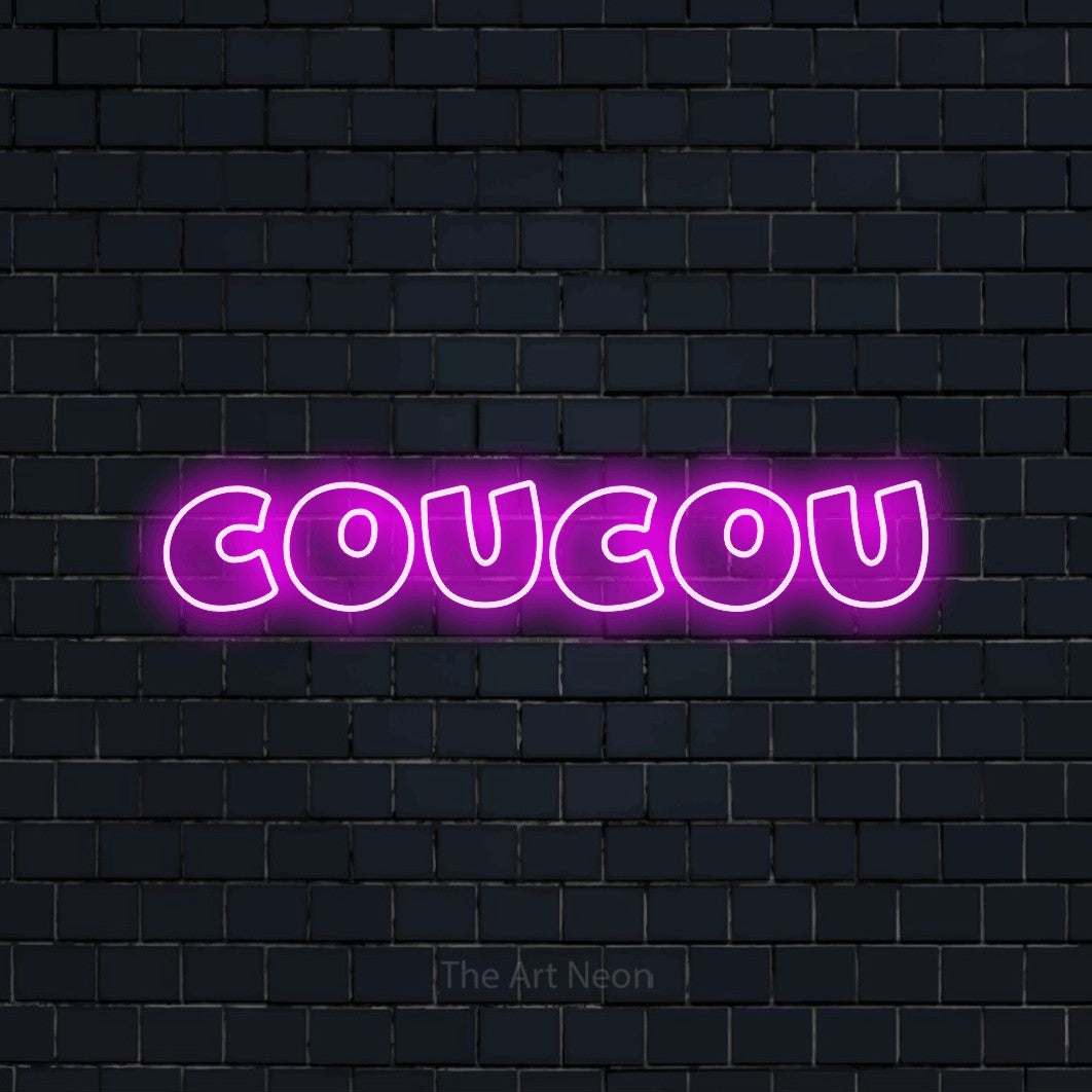 “Coucou” LED neon sign in pink, with wide lettering with irregular outlines, shown against a dark navy brick wall.