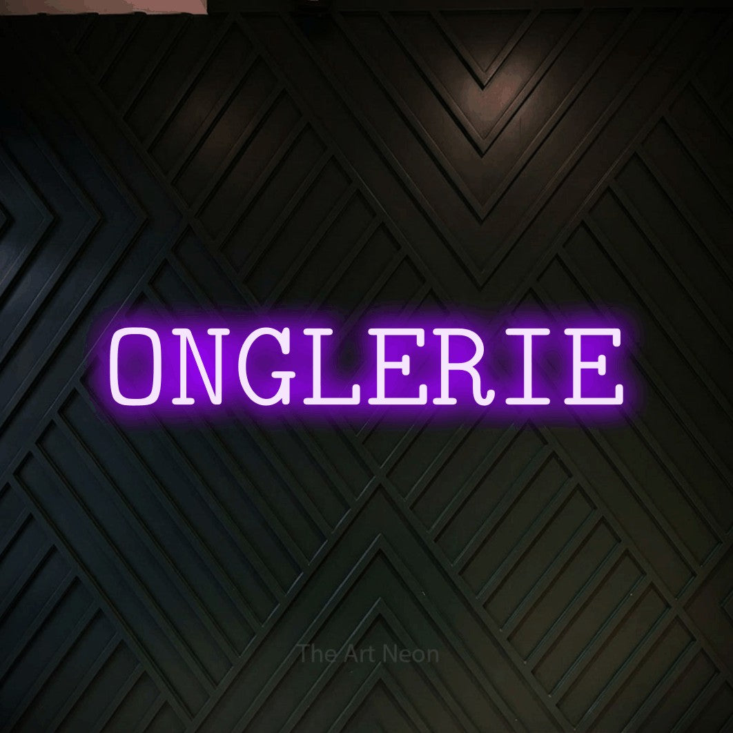 Décoration murale en néon LED « Onglerie » en violet, en caractères de machine à écrire, installée sur un mur en bois noir à motif chevron, pour un salon de beauté.