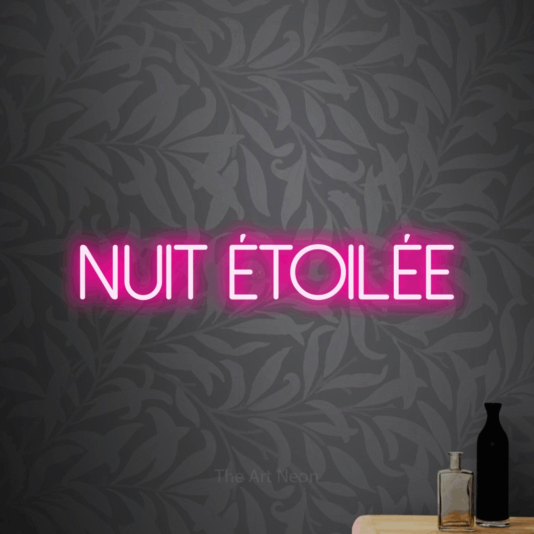 “Nuit étoilée” LED neon sign in hot pink, with thin sans-serif lettering, shown against grey botanical wallpaper.