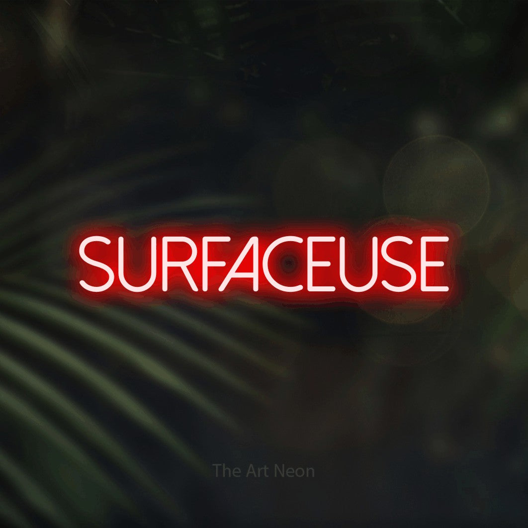 Aperçu d’une enseigne néon LED « Surfaceuse » en rouge, en lettres fines sans empattement, photographiée sur un fond flou de palmiers et de lumières bokeh, pour un décor de hockey.