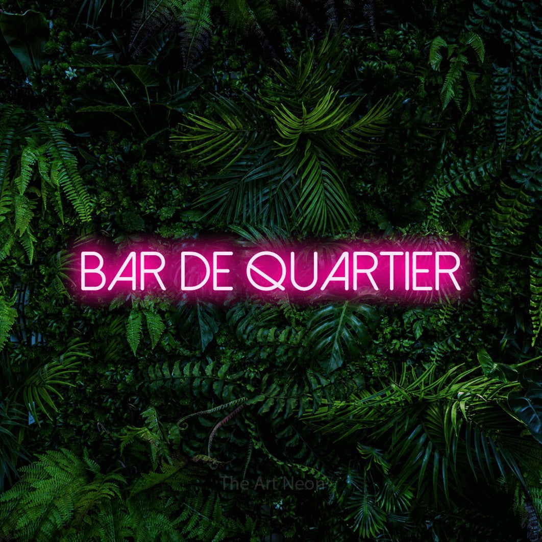 “Bar de quartier” LED neon sign in hot pink, with thin sans-serif lettering, shown against dense tropical foliage.