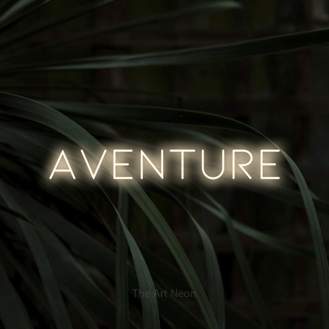“Aventure” LED neon sign in warm white, with thin, widely spaced lettering, shown against a close-up of dark foliage.