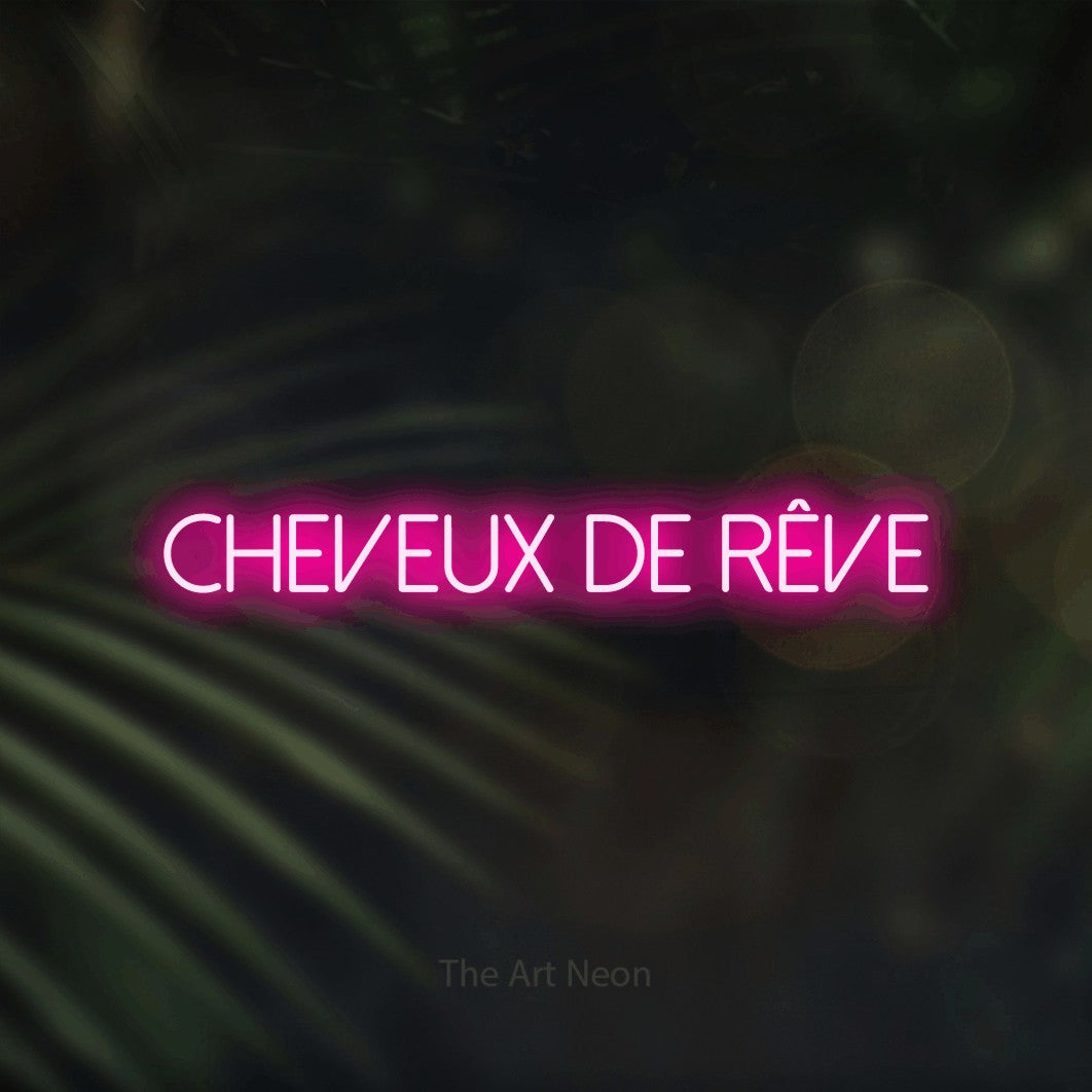 Composition en néon LED « Cheveux de rêve » en rose vif, en lettres fines sans empattement, mise en valeur sur un fond flou de palmiers et de lumières bokeh, pour un salon de beauté.