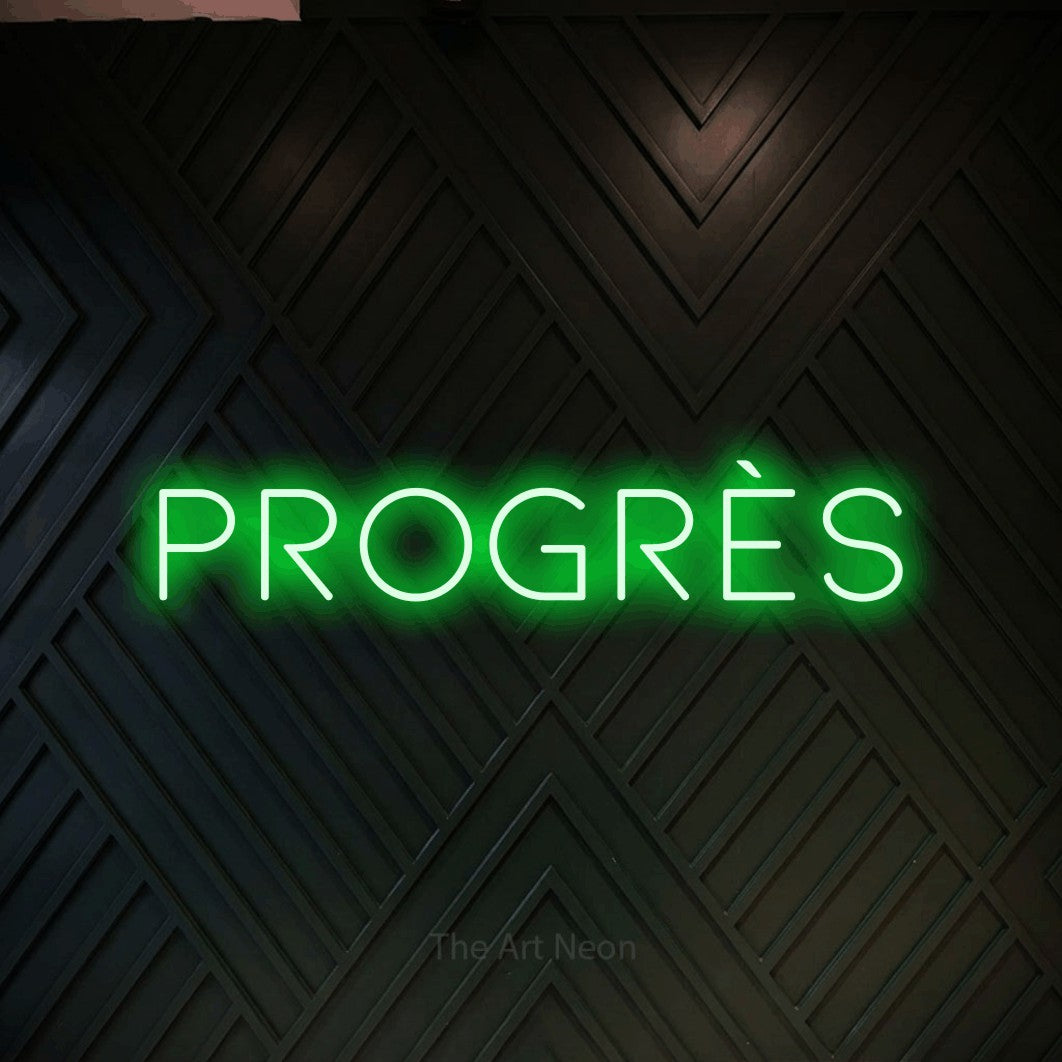 Néon LED « Progrès » en vert, en lettres fines et espacées, mis en scène sur un mur en bois noir à motif chevron, pour un espace d’entraînement.
