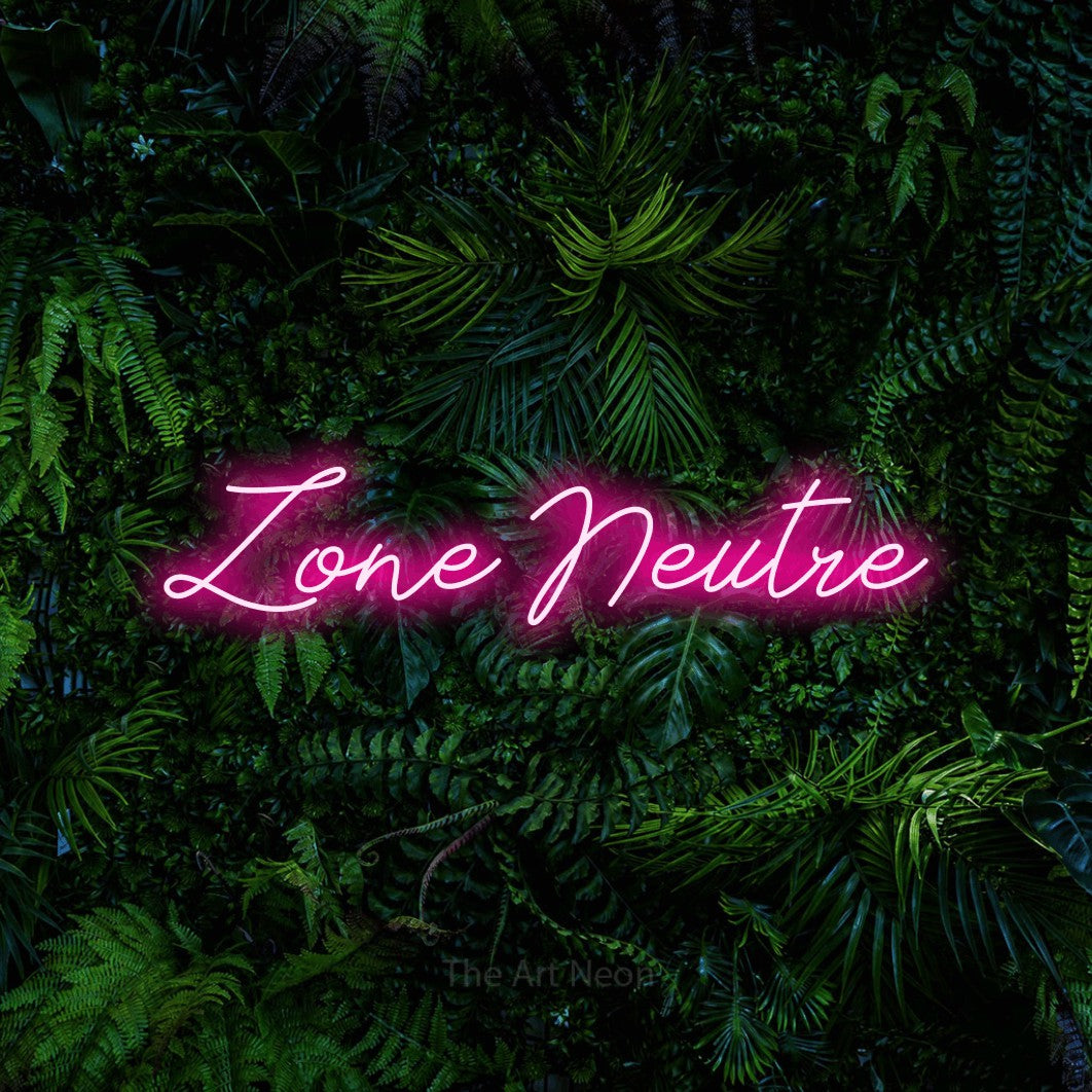 Composition en néon LED « Zone neutre » en rose vif, en lettrage cursif, mise en valeur devant un feuillage tropical dense, pour un décor de hockey.